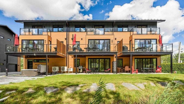Un edificio moderno a più piani con balconi, ampie finestre e un prato davanti.