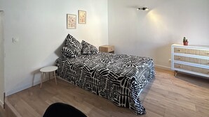 A bedroom with a bed, a small bedside table, a nightstand, a dresser, and a ceiling fan.