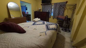 A bedroom with a bed, a dresser, a mirror, a wardrobe, and a radiator.