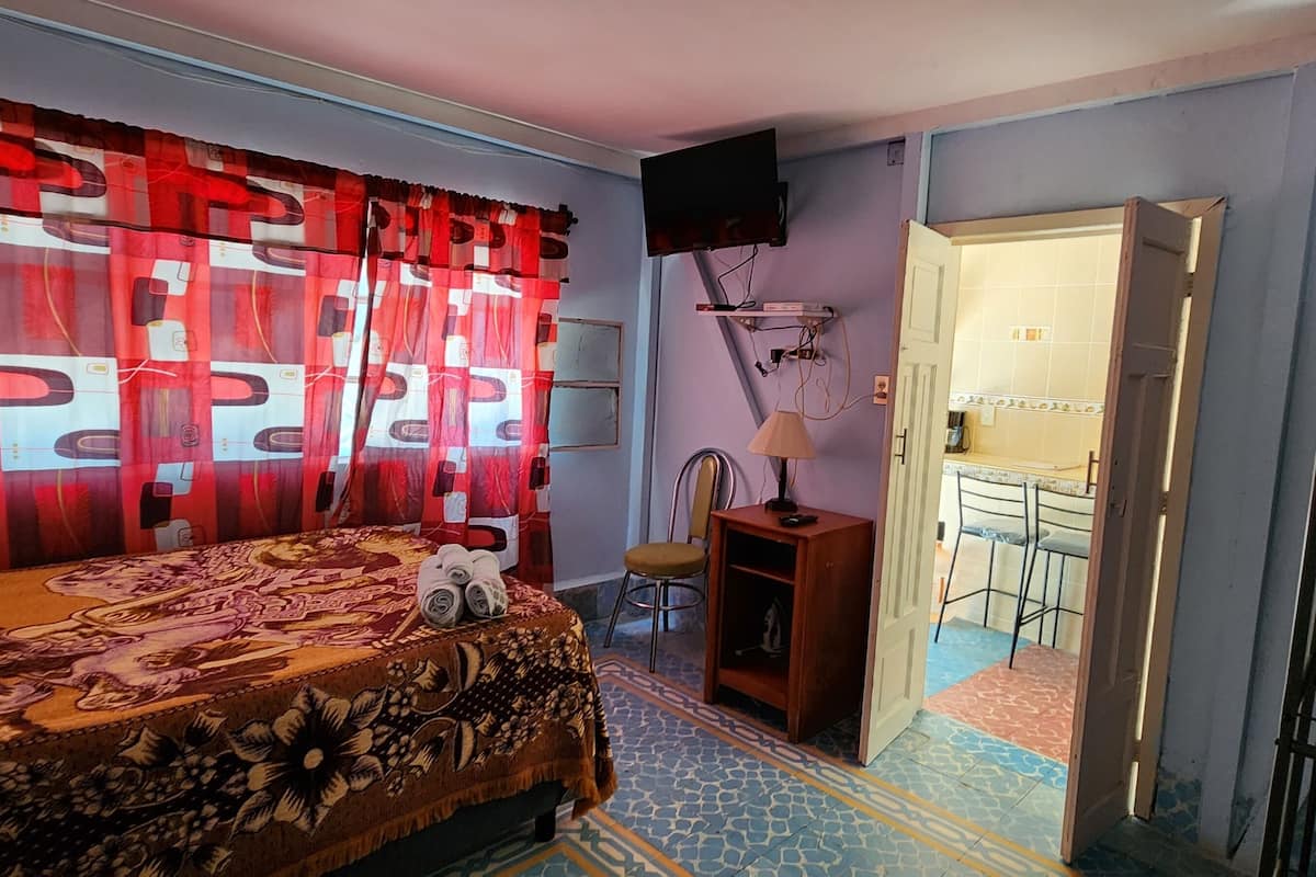 A bedroom with a bed, a chair, a TV, and a wardrobe.