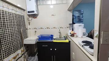 Uma cozinha compacta com pia, uma cesta azul, cafeteira e filtro de água.