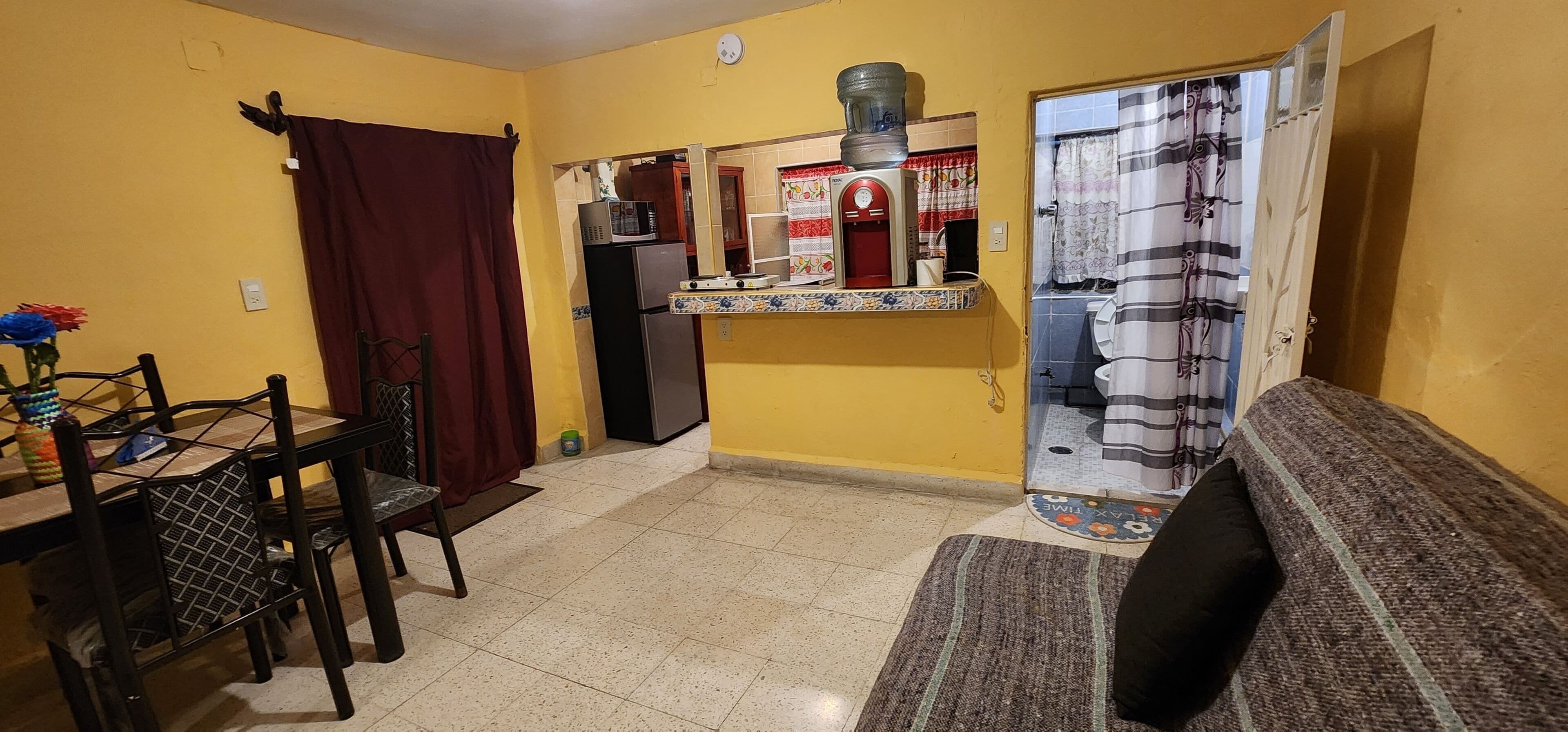 Un espacio habitable compacto con comedor, kitchenette y baño.