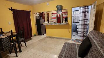 Un espacio habitable compacto con comedor, kitchenette y baño.
