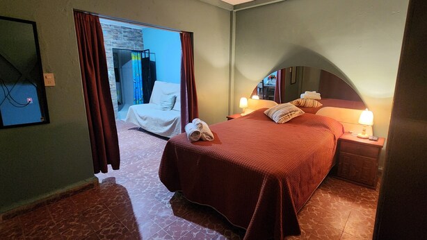 Una habitación de hotel con una cama, una silla, una mesita de noche y un espejo.