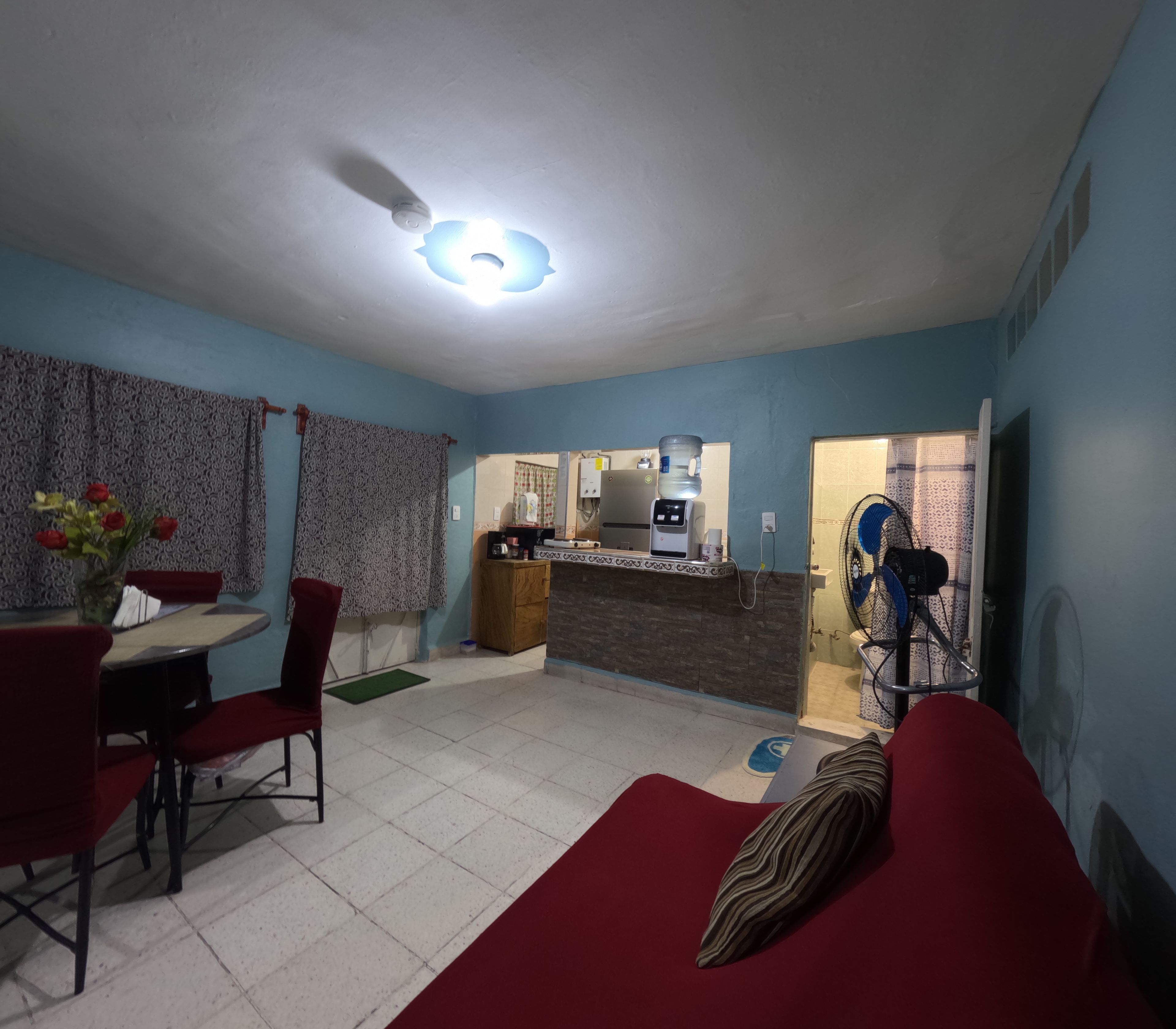 Un espacio habitable compacto con comedor, kitchenette y un baño pequeño.