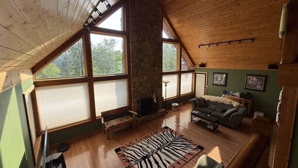 Une pièce spacieuse de style loft, dotée de grandes fenêtres, d’une cheminée en pierre et d’un coin salon confortable.