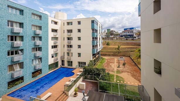 Un bâtiment moderne doté d’une piscine, de balcons et offrant une vue sur le paysage urbain lointain.