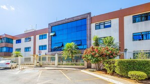 A modern building with a large glass facade, a gated entrance, and a parking area. - Apt w/ Balcony Sudoeste - Por0017 (Sudoeste e Octogonal)