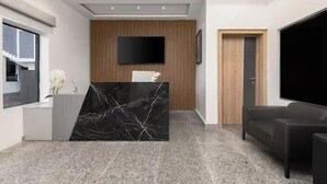 Una sala de estar moderna con una mesa de centro de mármol negro, un televisor de pantalla plana montado en la pared y un sofá de color oscuro.
