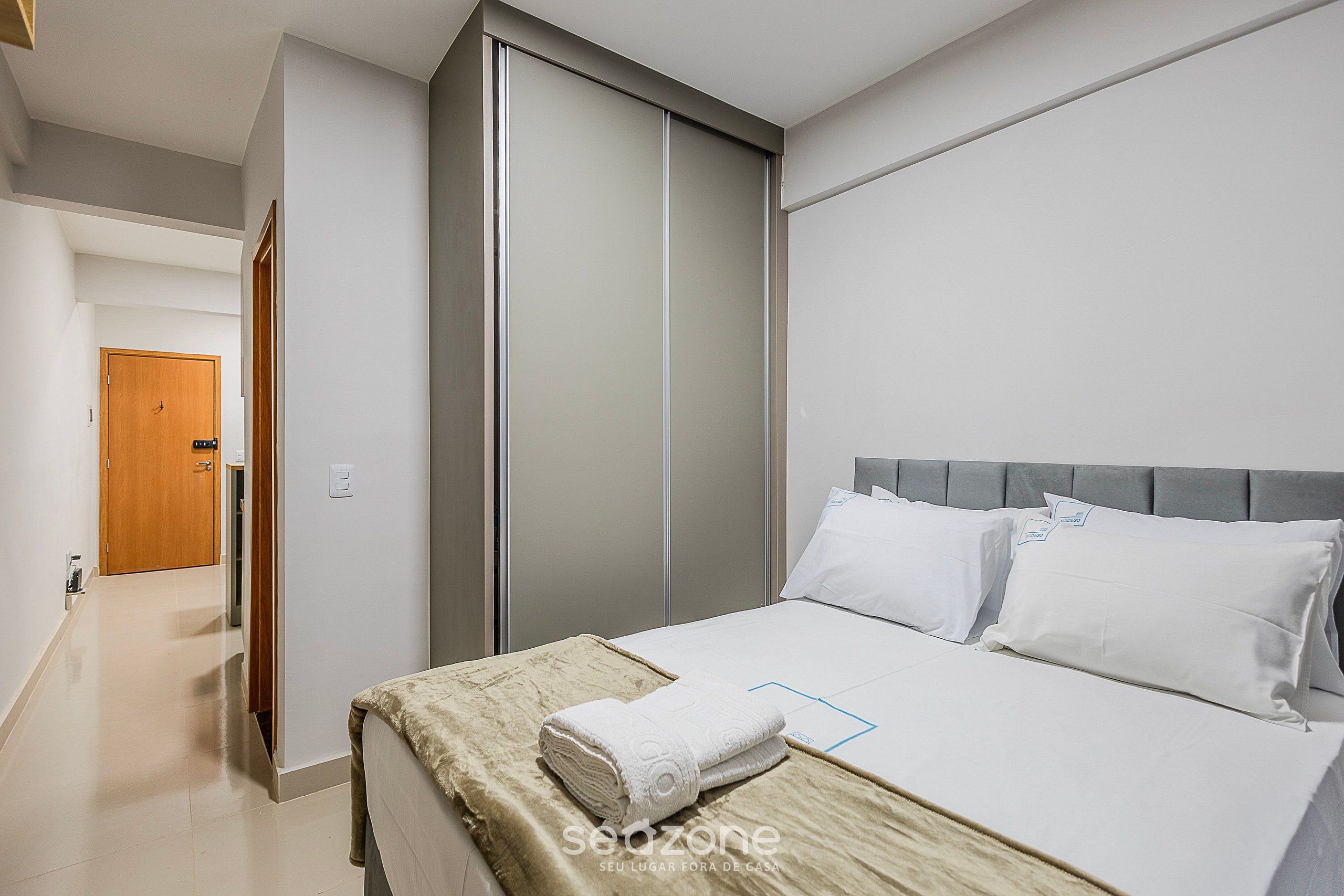 Ein Hotelzimmer mit einem Bett, einem Kleiderschrank und einer Tür zu einem weiteren Raum.