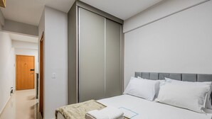 Ein Hotelzimmer mit einem Bett, einem Kleiderschrank und einer Tür zu einem weiteren Raum.