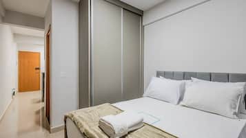 Ein Hotelzimmer mit einem Bett, einem Kleiderschrank und einer Tür zu einem weiteren Raum.