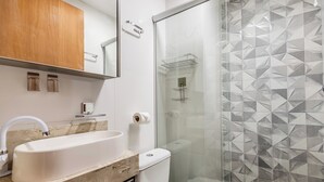 A bathroom with a white sink, a glass shower enclosure, and a patterned tile wall. - Charming Studio Taguatinga Norte - Rjt0104 (Taguatinga)