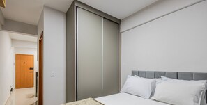 Een hotelkamer met een bed, een kledingkast en een deur naar een andere kamer.