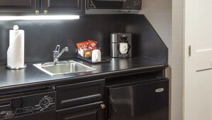 Une petite cuisine équipée d’un évier en acier inoxydable, d’une machine à café et d’un four à micro-ondes.