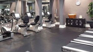 Une salle de sport équipée de machines de cardio, de bancs de musculation et d’un mur recouvert de miroirs.