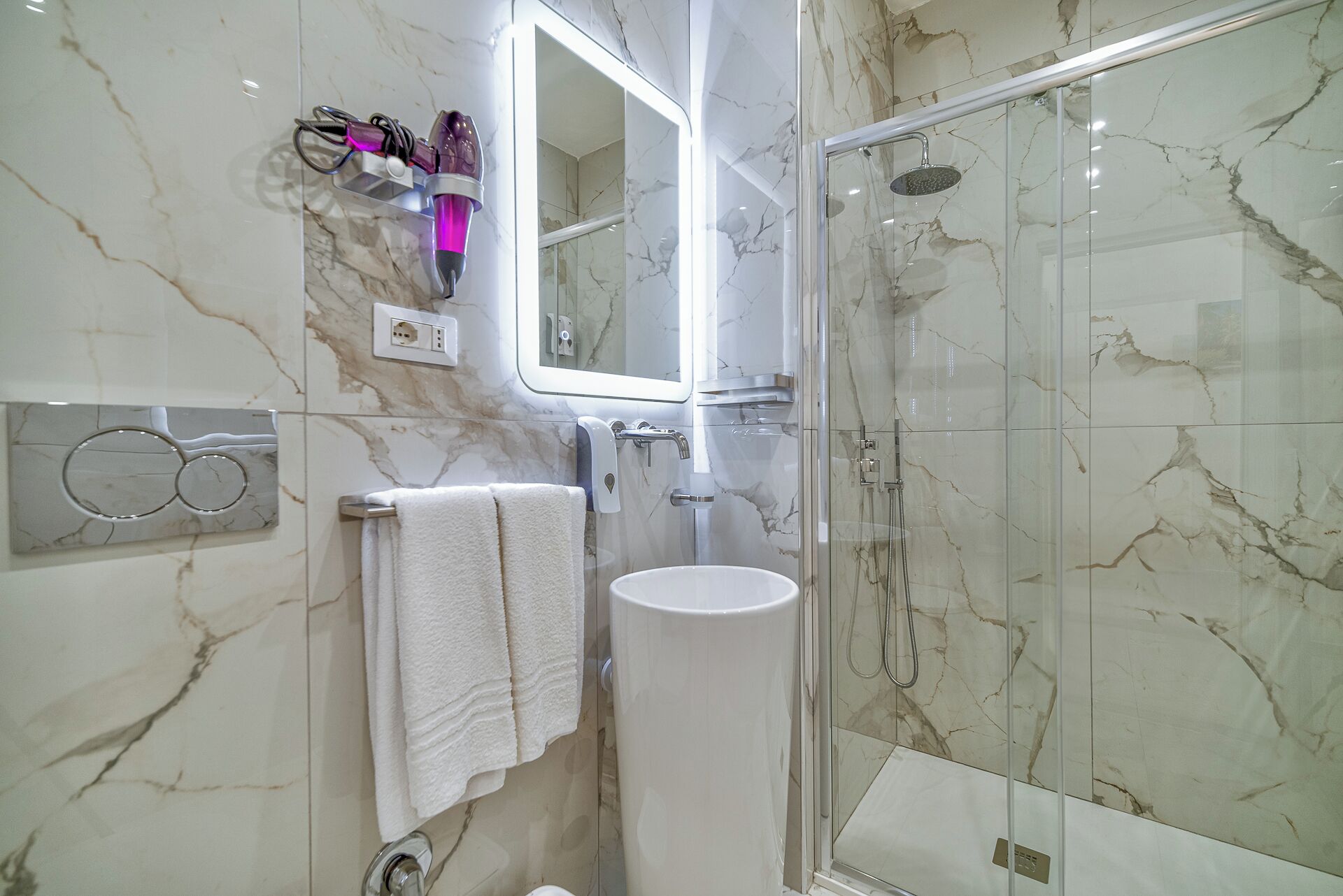 A bathroom with a glass-enclosed shower, a white sink, and a mirror above the sink.