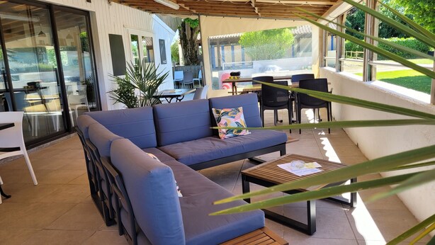 An outdoor seating area with a blue sofa, a wooden table, and chairs.