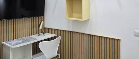 A modern office space with a flat-screen TV, a desk, a chair, and a wall-mounted air conditioner.