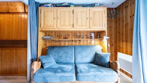 Une pièce avec un meuble en bois, un canapé bleu et un téléviseur.