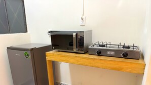Eine kompakte Küche mit einem Hisense-Kühlschrank, einer Mikrowelle und einem Superflam-Gasherd auf einem Holzboden.