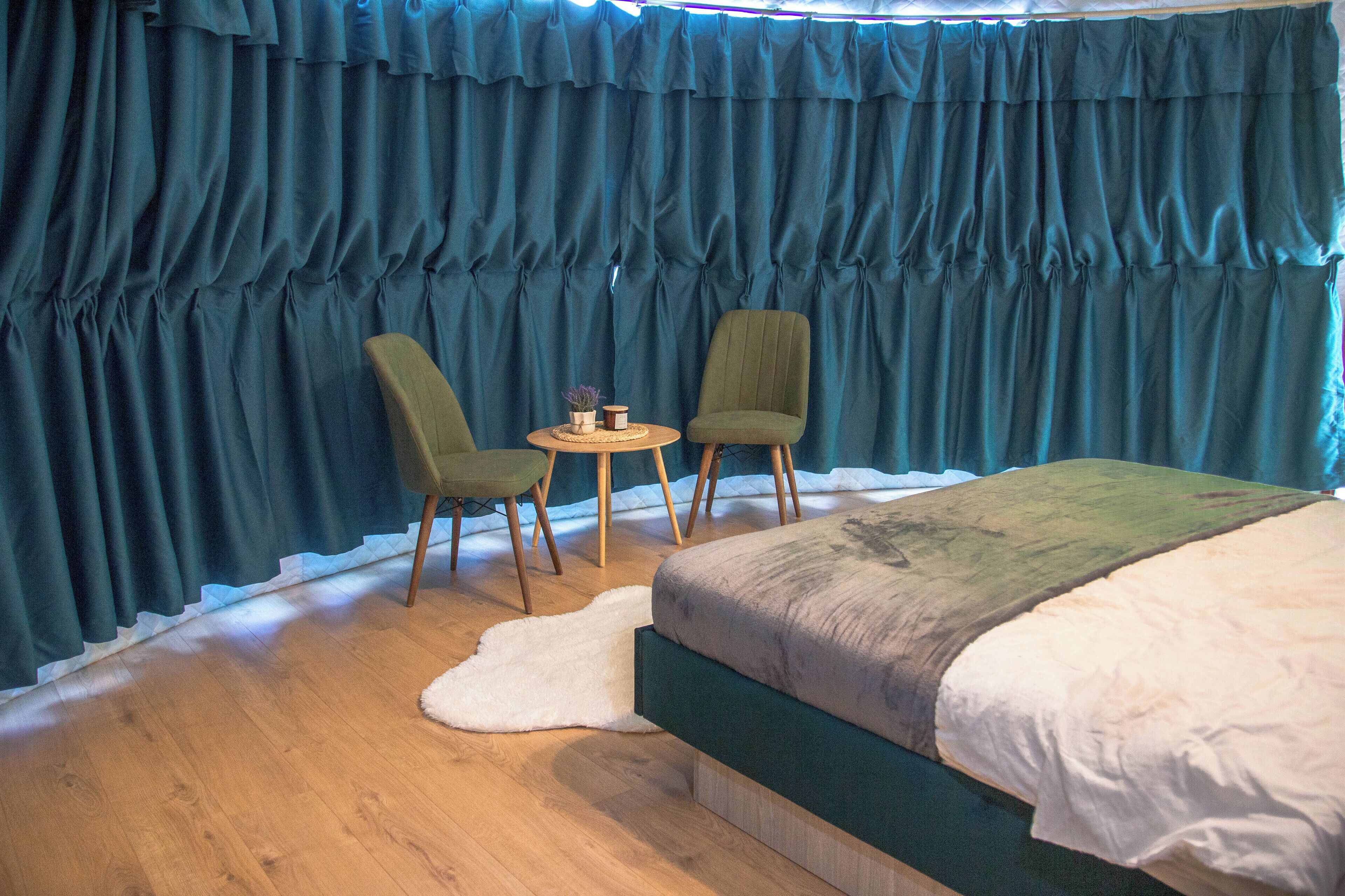 Un dormitorio con una cama, dos sillas, una mesita y una alfombra blanca.