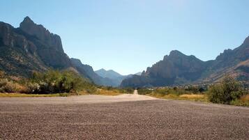 A paved road leading through a mountainous area with sparse vegetation.