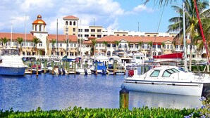 A marina with boats docked, a building with a clock tower, and a clear sky.