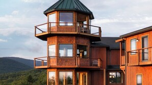 Eine mehrstöckige Holzhütte mit einem zentralen Turm, Sitzgelegenheiten im Freien und einer Feuerstelle.