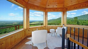 Eine Holzhütte mit großen Fenstern, die Blick auf grüne Hügel bietet.