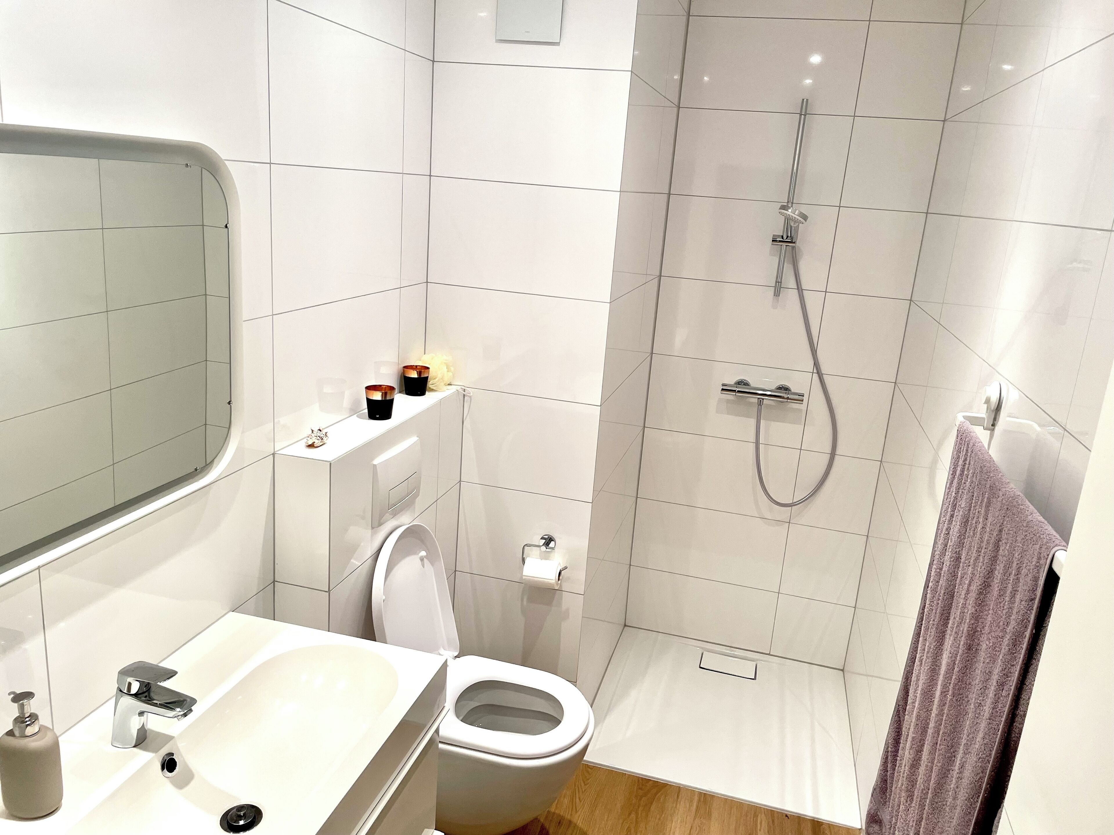 A modern bathroom with a white sink, toilet, and shower.