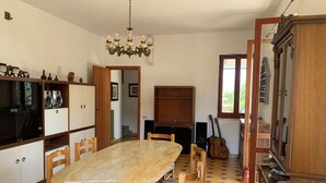 A dining area with a marble table, wooden chairs, a chandelier, and a guitar. - Villa Panorama (Bivio Acquavella)