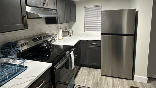 A modern kitchen with stainless steel appliances, dark cabinetry, and a white countertop. - Charming 2-bedroom cottage in lovely Fort Walton Beach (Fort Walton Beach)