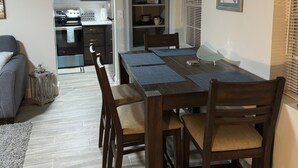 A dining area with a wooden table and chairs, a kitchen in the background, and a framed picture on the wall. - Charming 2-bedroom cottage in lovely Fort Walton Beach (Fort Walton Beach)
