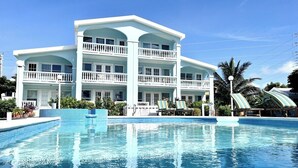 A large building with a swimming pool, multiple balconies, and lounge chairs. - A6 Modern 3BR with Stunning Views! (San Pedro)
