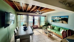 A dining area with a table and chairs, a sofa, a television mounted on the wall, and a ceiling fan. - A6 Modern 3BR with Stunning Views! (San Pedro)