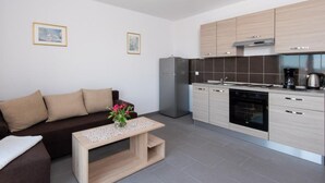 Une cuisine moderne avec des meubles de couleur bois clair, un réfrigérateur en acier inoxydable et une machine à café.