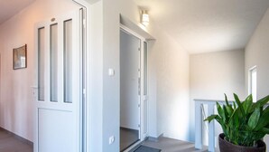 Un couloir avec des portes blanches, une plante en pot et un luminaire.