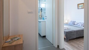 Une chambre à coucher moderne avec un lit, une table de chevet et une petite table en bois sur laquelle sont posés des magazines.