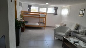 Una habitación con una cama nido, un sofá, una mesita de centro y una planta en maceta.