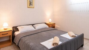 Un dormitorio ordenado con cama, mesitas de noche y una ventana.