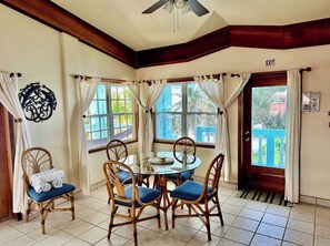 A dining area with a round table, chairs, and a ceiling fan.