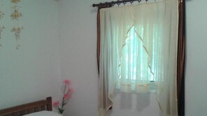 A bedroom with a bed, a window with a sheer curtain, and a wall decoration. - Apartments Marija in National Park Area - One Bedroom Apartment in Ground Floor (Starigrad-Paklenica)