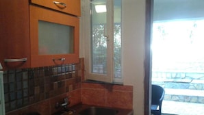 A kitchen with two sinks, a window, and a view of a stone patio. - Apartments Marija in National Park Area - Studio Apartment (Starigrad-Paklenica)