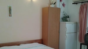 A bedroom with a bed, a wooden wardrobe, a small white cabinet, and a desk with a chair. - Apartments Marija in National Park Area - Studio Apartment (Starigrad-Paklenica)