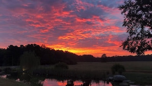 Ein See im Abendlicht mit Stühlen und Tisch am Ufer.