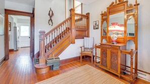 A wooden staircase with a railing, a wooden cabinet with a mirror, and a chair with a towel.