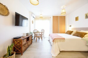 A bedroom with a bed, bedside table, TV, and a dining area with chairs and a table. - Cozy Loft Matias Benalmadena Malaga (Benalmádena)