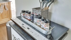 Una cocina con un mueble para especias incorporado que contiene varias especias y un batidor en una cesta.