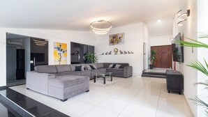 A modern living room with a grey sectional sofa, a glass coffee table, and a flat-screen TV mounted on the wall. - Casa Blau (Cali)